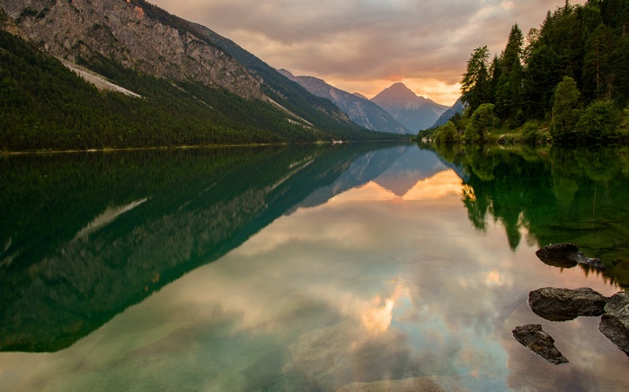 Lake reflecting mountains at sunset