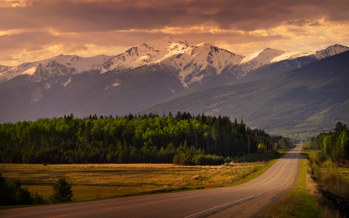 Road leading to snow-capped mountains at sunset