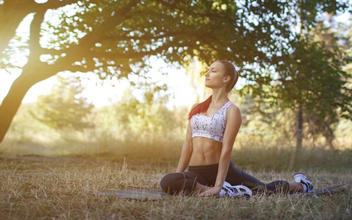Woman doing yoga outdoors under a tree