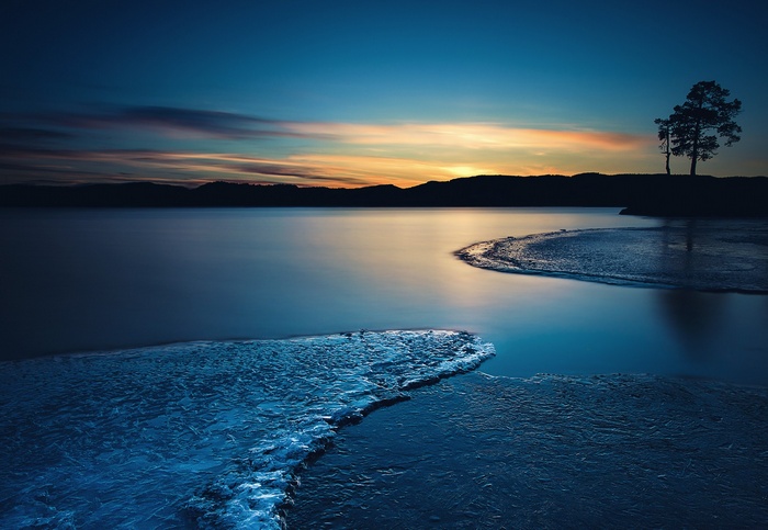 Frozen lake at sunset with silhouetted trees