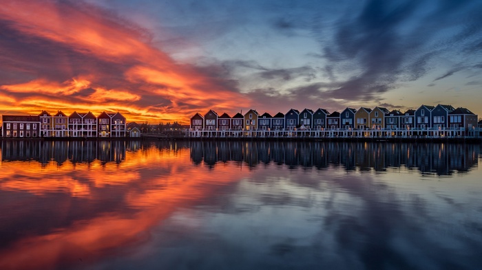 Colorful houses reflecting in water at sunset