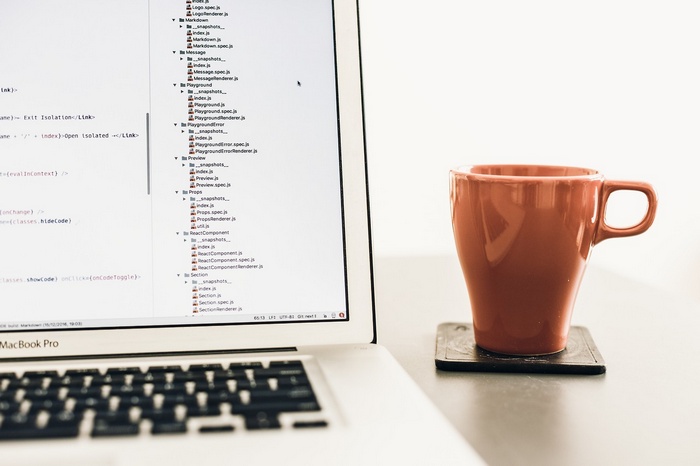 MacBook Pro with code and coffee cup