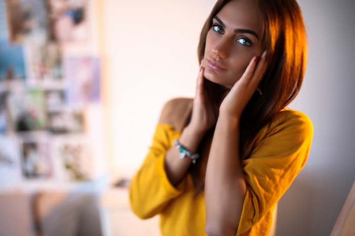 Woman with tanned skin and red nails, hand on face