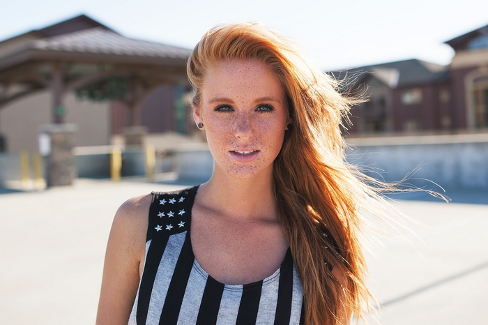 Redhead woman with freckles wearing a striped tank top