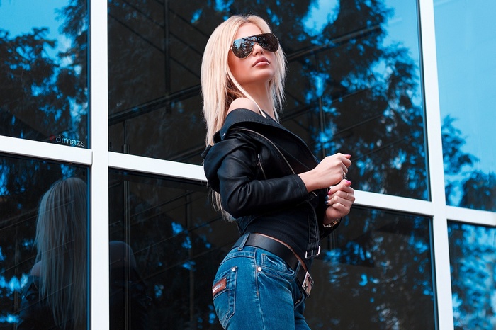 Woman in leather jacket and jeans wearing sunglasses