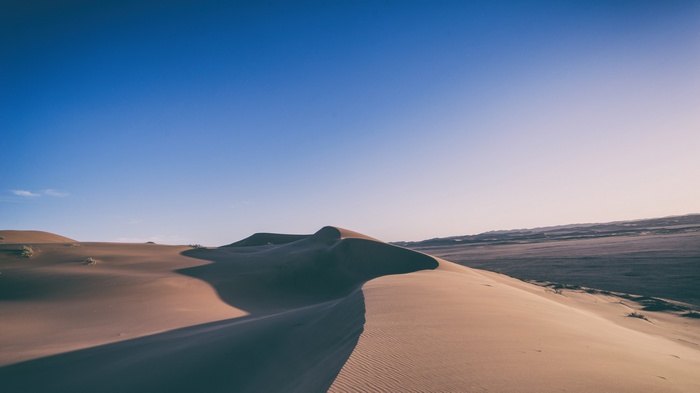 Desert sand dunes under a clear blue sky