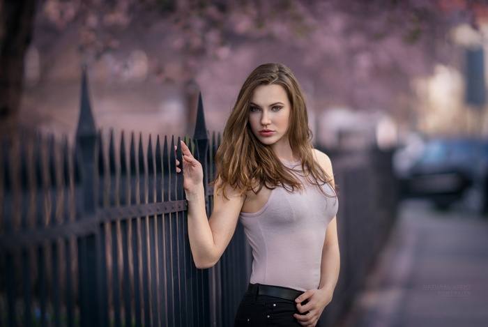 Woman with long brown hair leaning on a fence