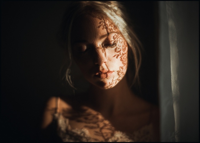Woman with lace pattern shadow on face