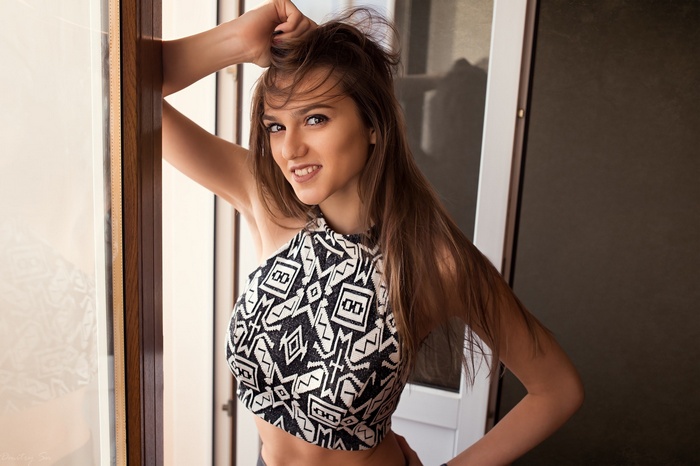 Woman in patterned crop top leaning by window