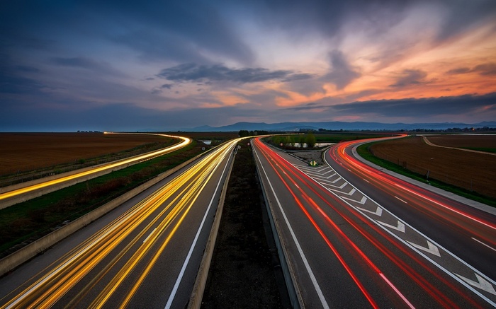 Highway light trails at dusk with clouds