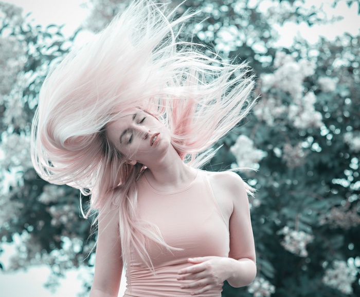 Woman with long pink hair flipping outdoors
