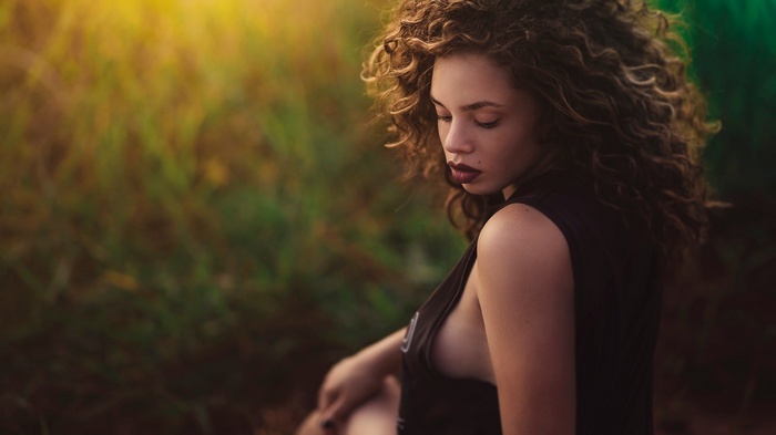 Woman with curly hair in a tank top outdoors