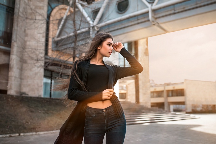 Woman with long hair wearing black sweater and jeans outdoors