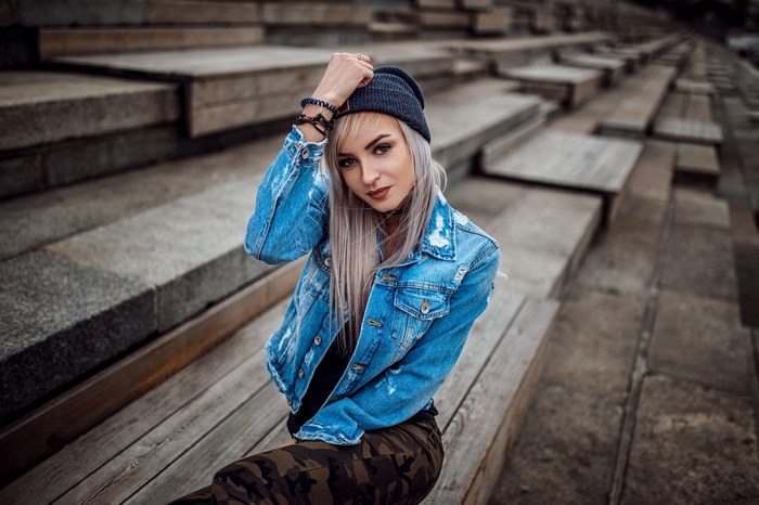 Woman in denim jacket and beanie sitting on steps