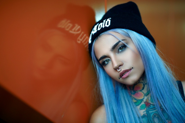 Woman with blue hair and tattoos wearing a beanie