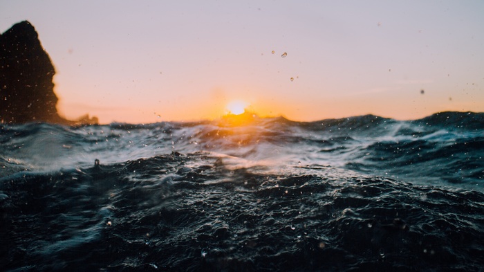 Sunset over ocean waves with rock formation