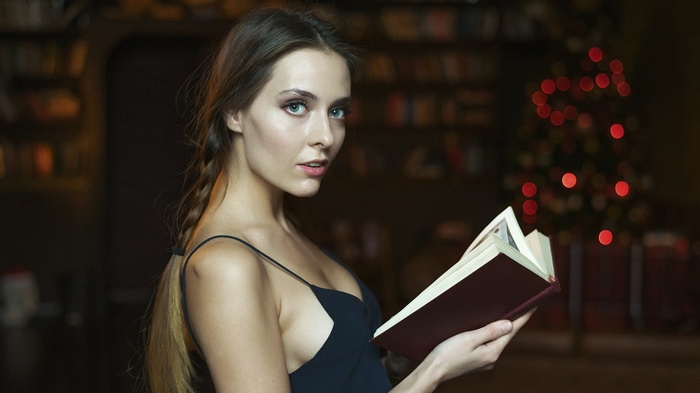 Woman reading a book in a library with Christmas tree