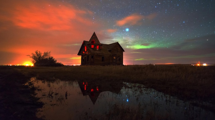 Abandoned house under the aurora borealis and stars