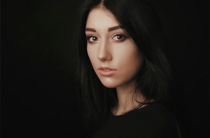 Portrait of a woman with black hair against a black background