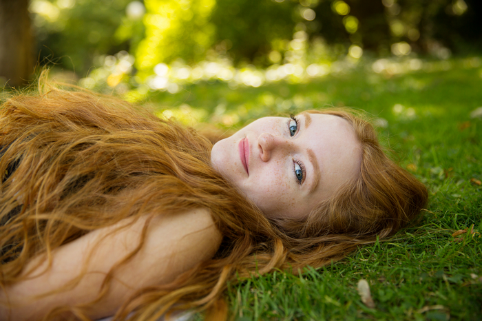 Young redhead woman lying in grass outdoors
