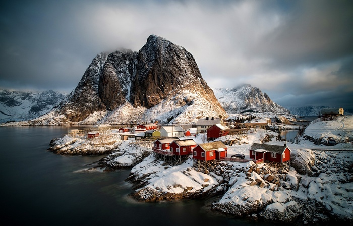 Red fishing cabins on a snowy coast in Norway