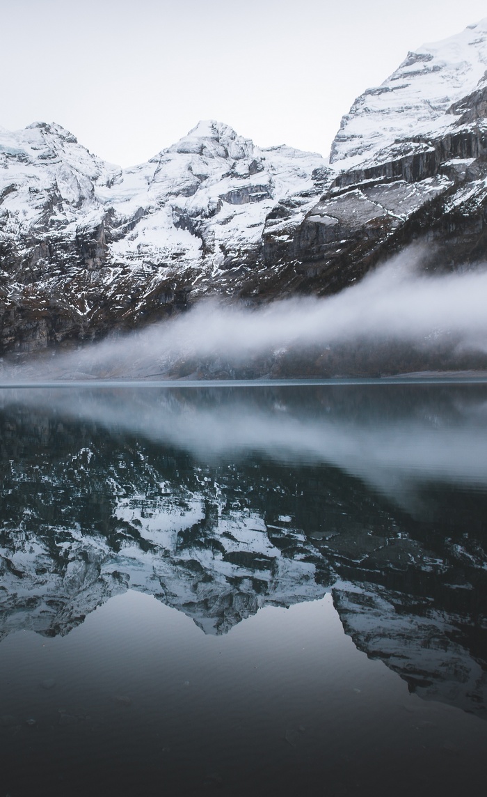 Snowy mountains reflected in a misty lake