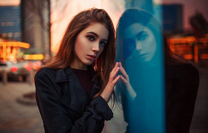 Woman in black coat reflected in glass outdoors