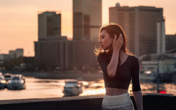 Woman with auburn hair in a cityscape at sunset