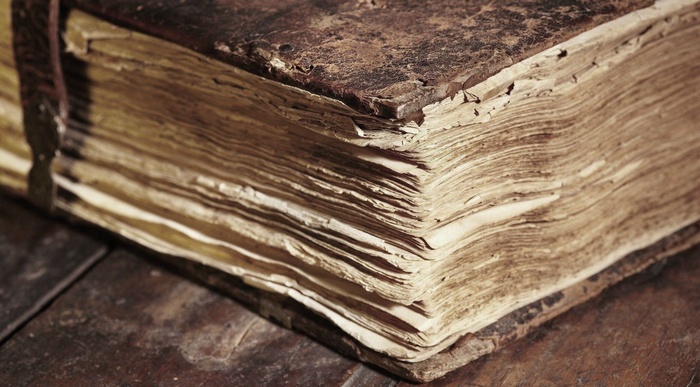 Close-up of an old, worn book with thick pages