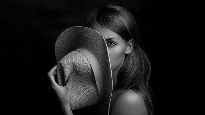 Woman with hat covering face, monochrome portrait