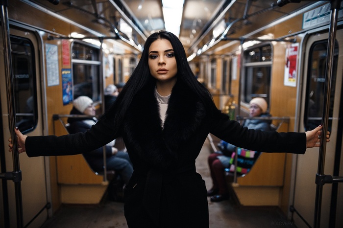 Woman with black hair in a black coat in a subway car