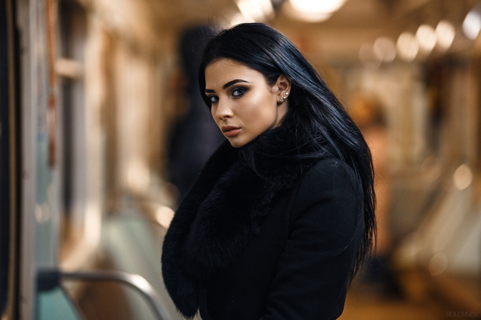 Woman with black hair in a black coat in the metro