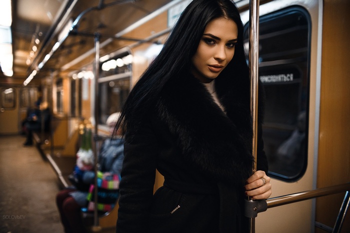 Woman with black hair in a black coat on a subway