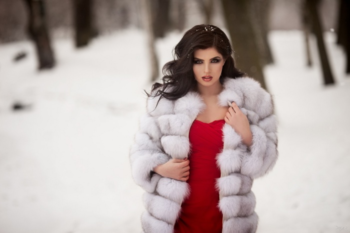 Woman in red dress and white fur coat in snow