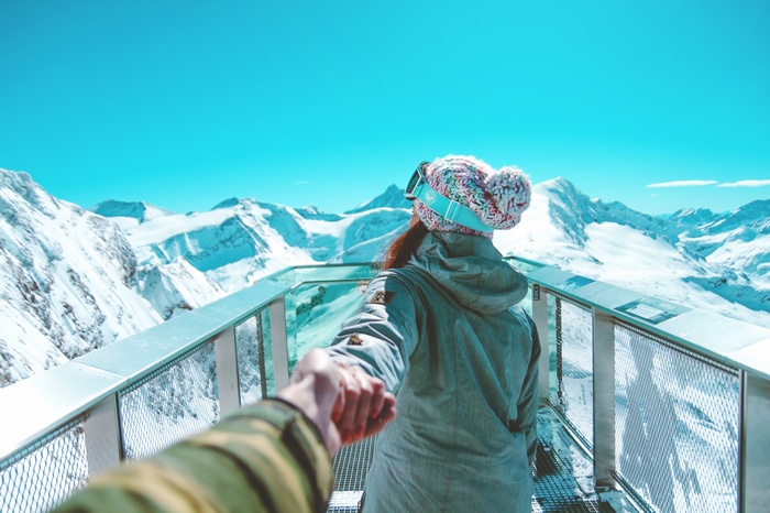 Couple holding hands on a snowy mountain observation deck