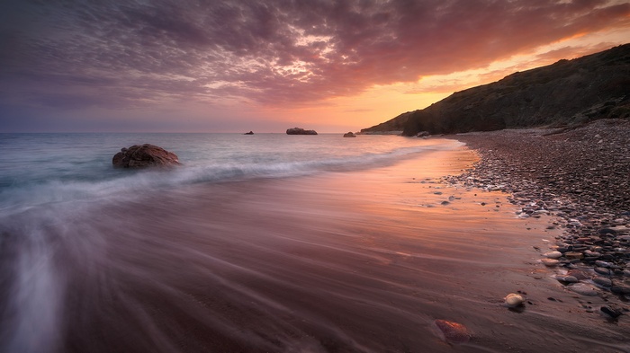 Sunset over a rocky beach with waves