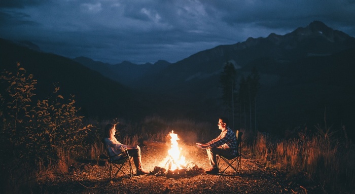 Couple sitting by campfire in mountains at night