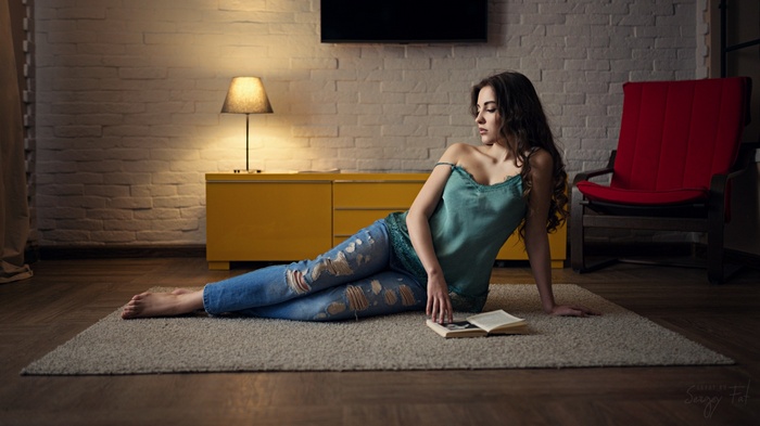 Woman in torn jeans sitting on floor with book