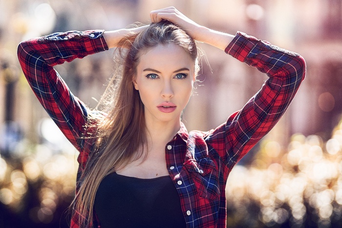 Woman with hands on head wearing a plaid shirt