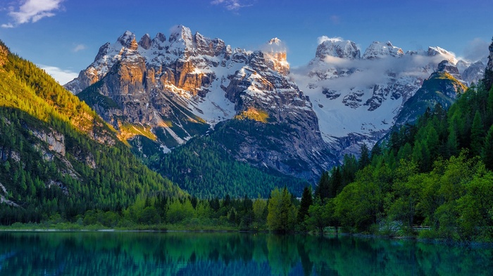 Snow-capped mountains reflected in a lake with pine trees