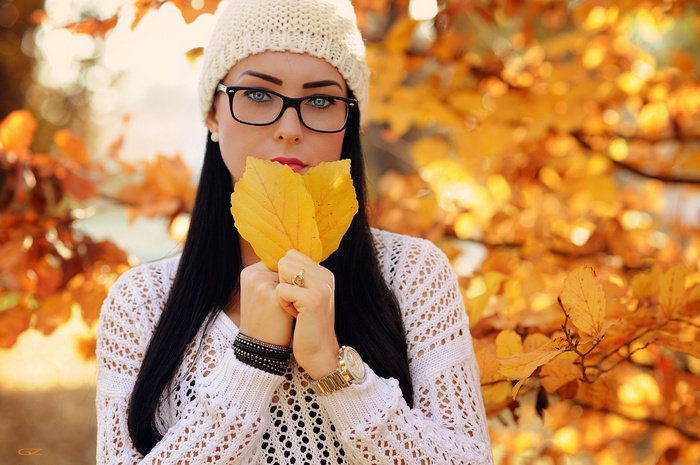 Woman in glasses holding autumn leaves