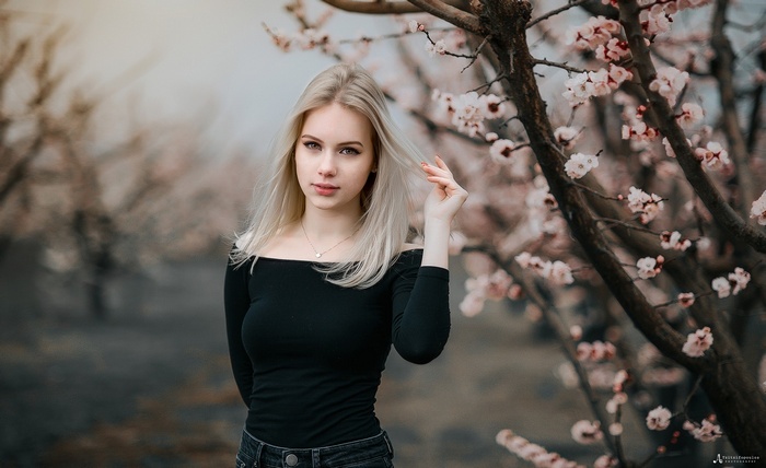 Woman with blonde hair in a black off-the-shoulder top outdoors