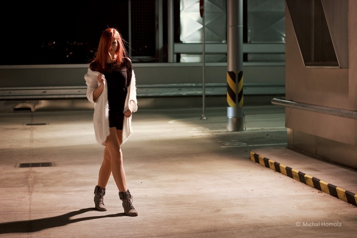 Redhead woman in black dress and white cardigan outdoors at night
