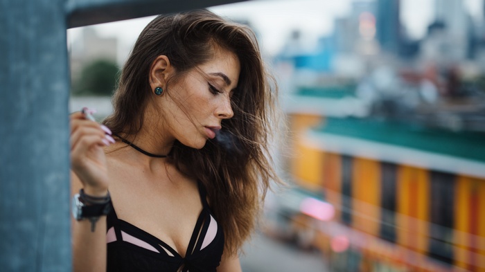 Woman smoking on a rooftop with city background