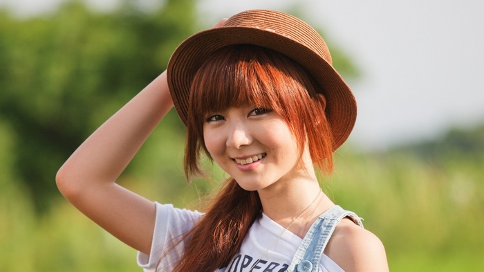 Asian woman wearing a hat and overalls