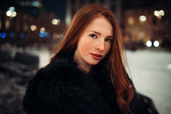 Redhead woman with freckles in a fur coat at night