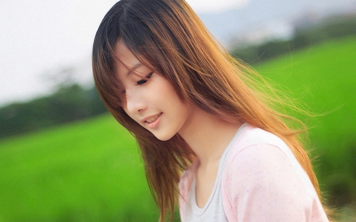 Asian woman with auburn hair in a pink shirt