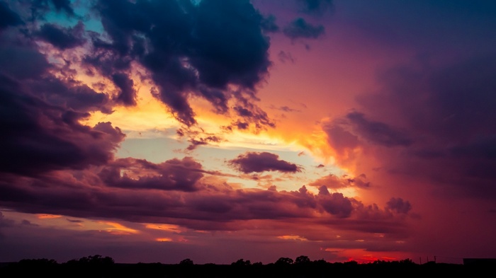 Dramatic sunset with colorful clouds over silhouetted landscape