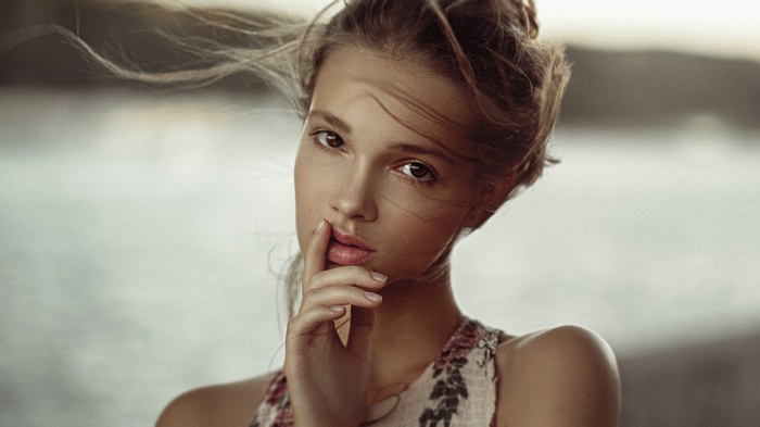 Portrait of a young woman with hand on lips