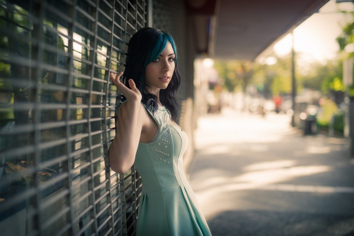 Woman with blue streaks in hair leaning against a metal grate